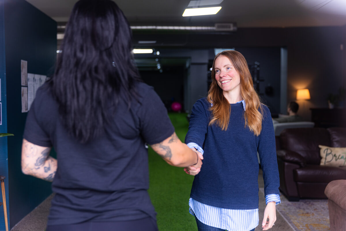 An eFIT team member greeting someone with a handshake in the front lounge